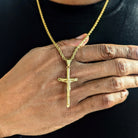 A person wearing an 18K gold classic crucifix pendant on a gold-plated chain.