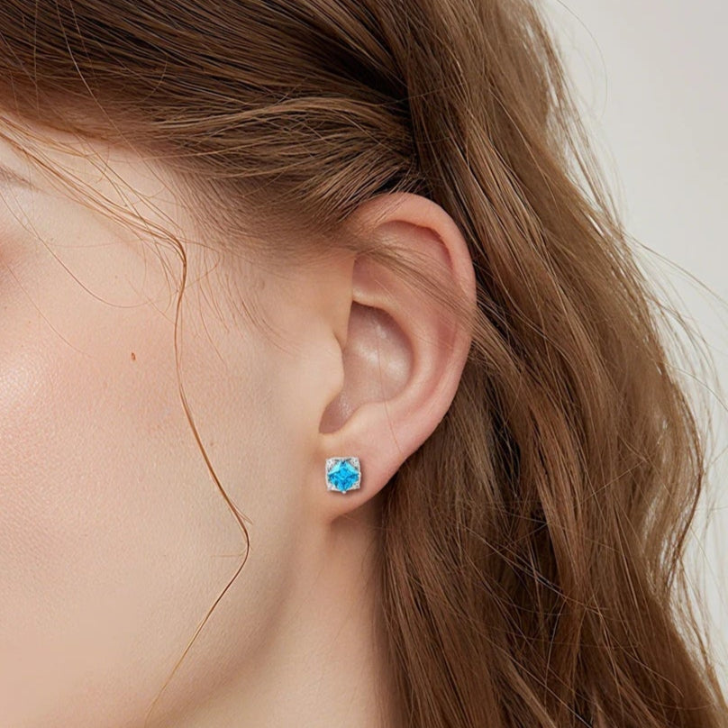 Close-up of a woman wearing blue earrings with a neutral background