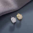 A pair of 18K gold diamond-studded fire emoji grillz on a grey surface.