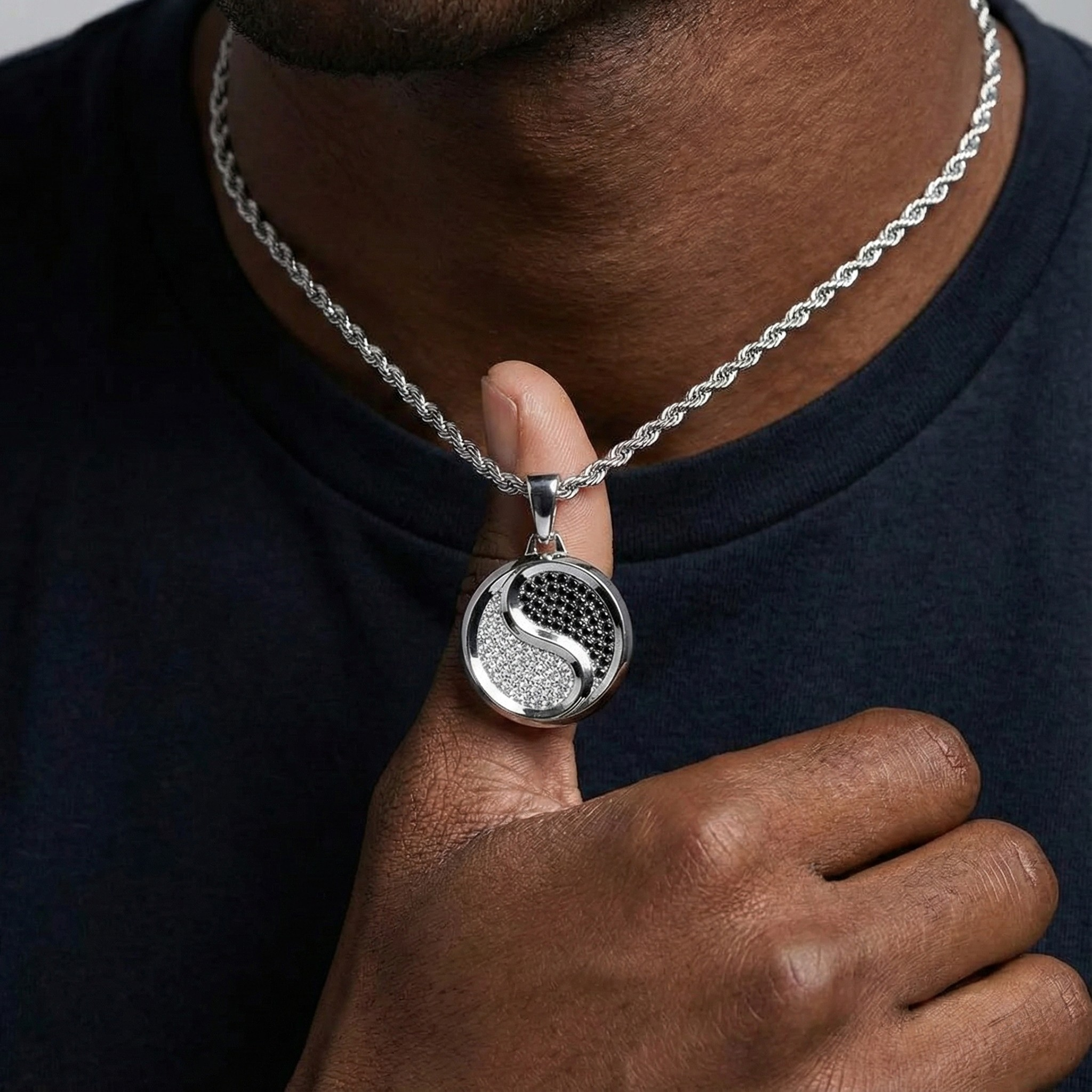 Person wearing a silver necklace with a yin yang pendant