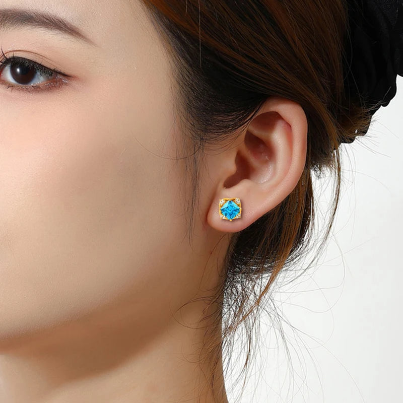 Close-up of a person wearing a blue gemstone earring on a white background