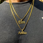 Gold necklaces with name pendants on a gray shirt