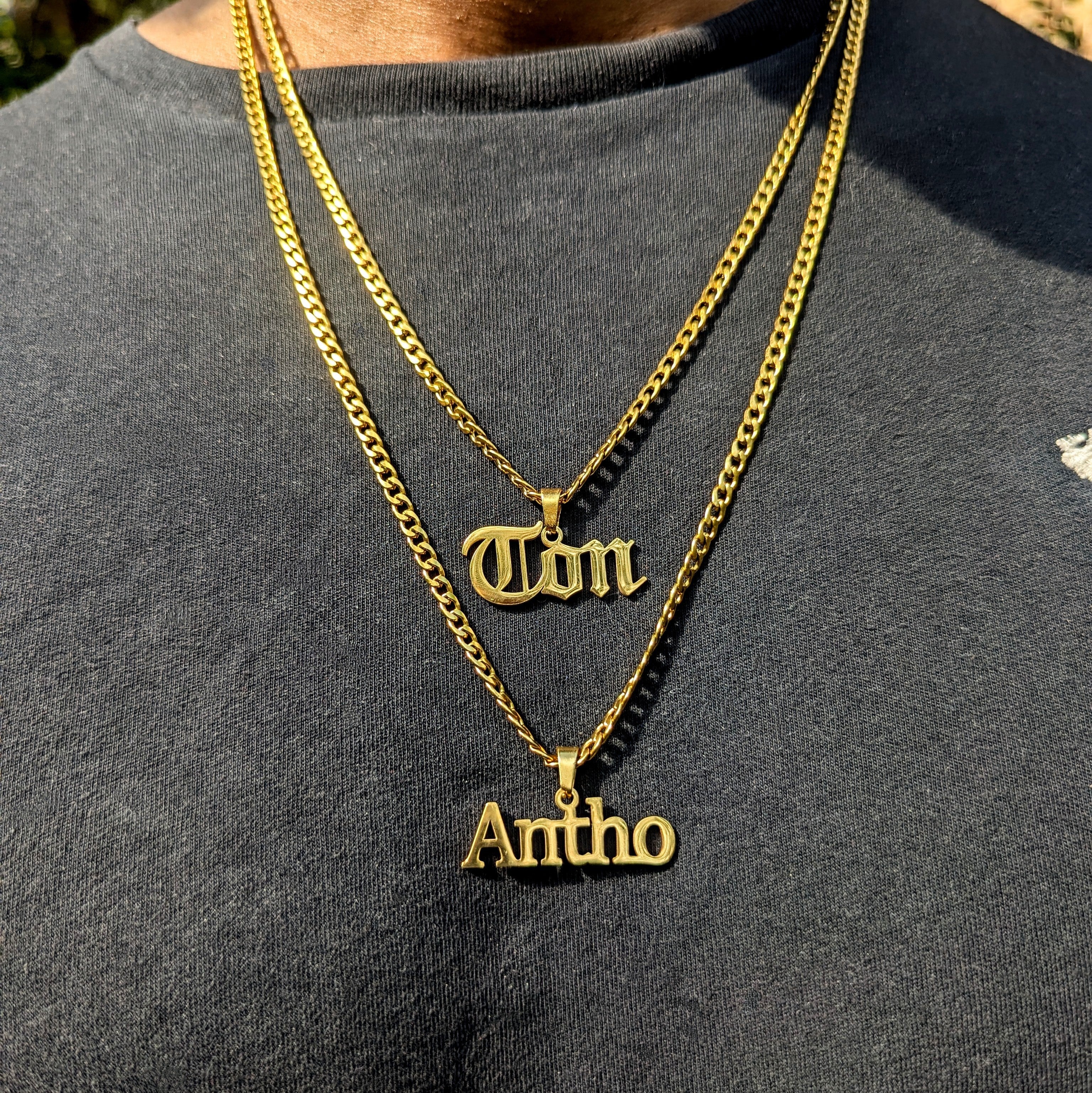 Gold necklaces with name pendants on a gray shirt