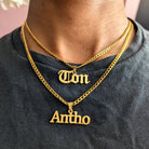 Gold necklaces with 'Ton' and 'Antho' pendants on a person wearing a dark shirt.