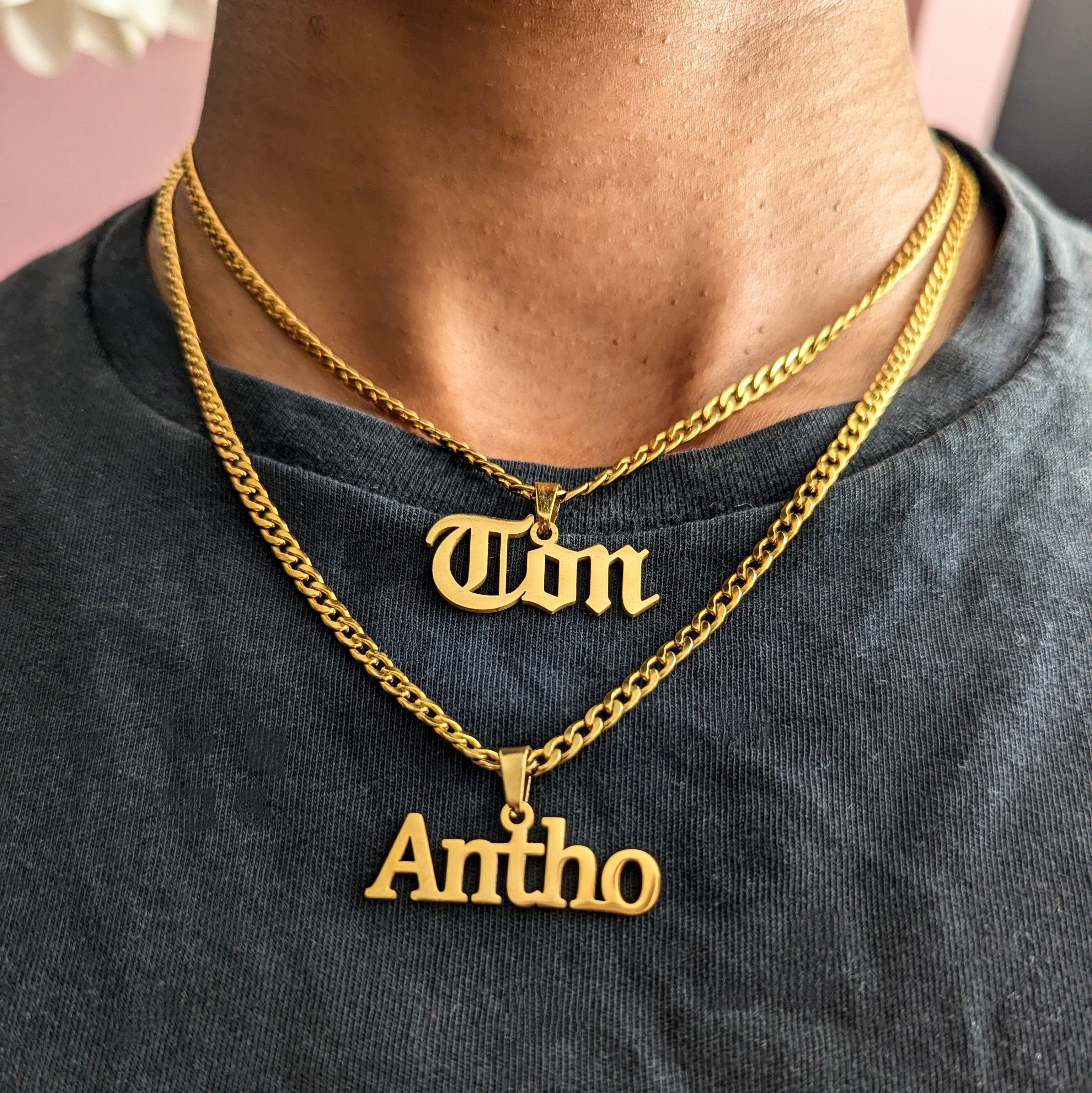 Gold necklaces with 'Ton' and 'Antho' pendants on a person wearing a dark shirt.
