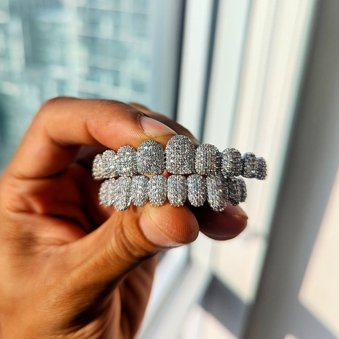 A set of 18k gold diamond grillz in various designs, showcasing the top and bottom teeth with sparkling diamonds.